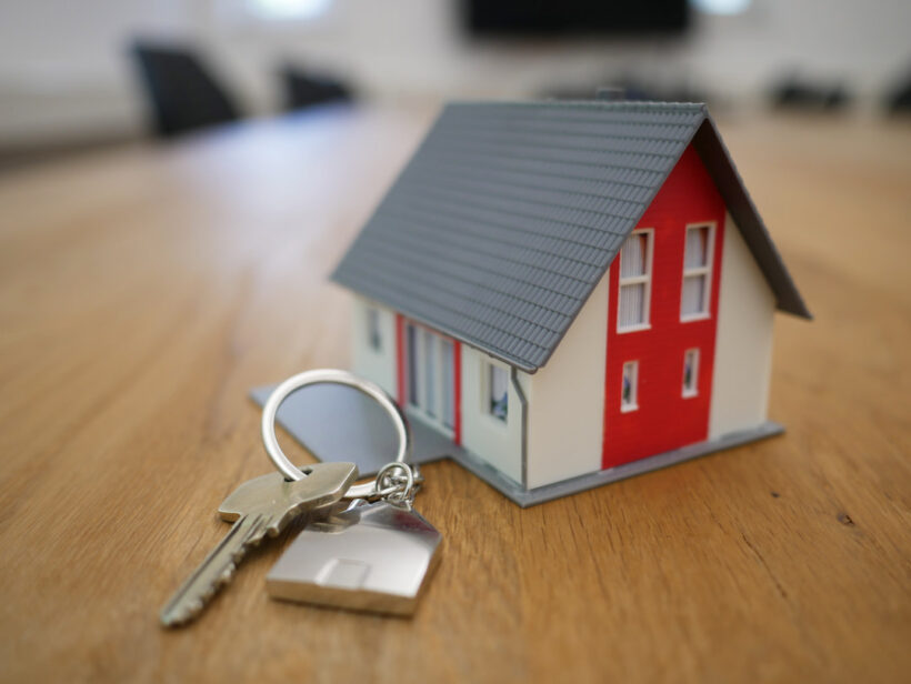 Mały domek stoi na stole obok kluczy do domu kanadyjskiego